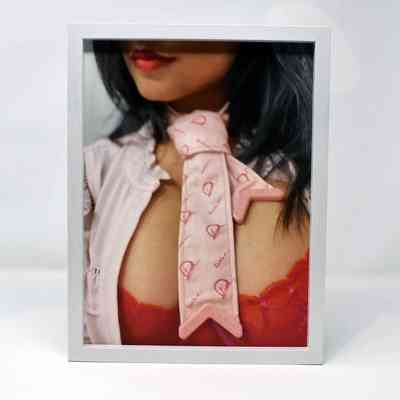 Framed colour portrait of Zakkiya Khan who has a red top on, pink jacket and pink tie.