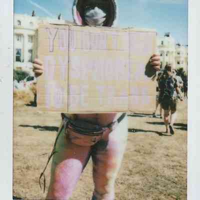A person holds a sign reading "You don't need dysphoria to be trans".