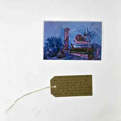 A painting of still life in blues and pinks and a brown luggage tag.