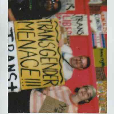 Three people are holding signs with messages in a vibrant room.