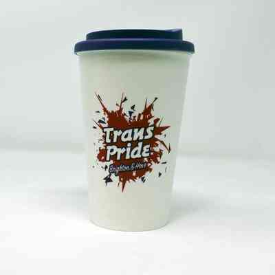 White plastic reusable coffee cup with dark purple lid. There is a red and purple logo visible on the cup which reads "Trans Pride Brighton & Hove"