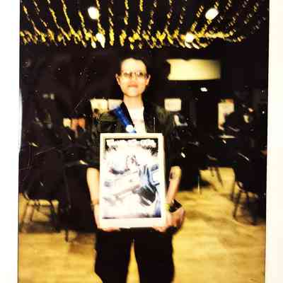 A person is holding a framed picture in a dimly lit room with string lights overhead.