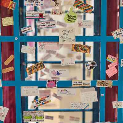 A close-up photograph of a photo booth which is painted pink and blue and is covered in stickers which are all about transgender lives, activism and phrases.