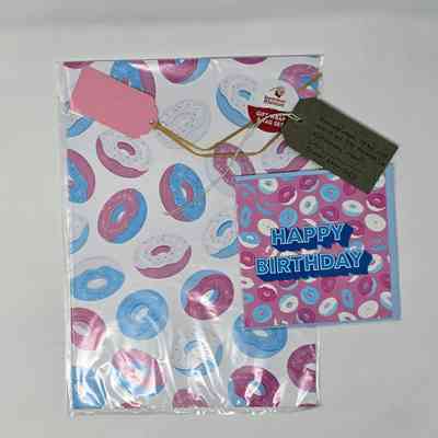 Matching gift wrap and birthday card illustrated with cartoon frosted donuts in pink, blue and white. With a brown, handwritten luggage tag.