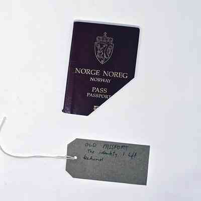 A Norwegian Passport with the bottom left corner cut off. With a brown, handwritten luggage tag.