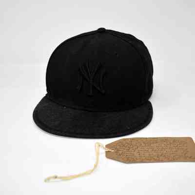 Black baseball cap lying next to a brown tag.