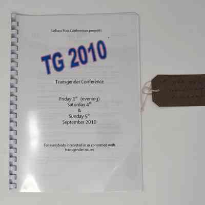 The image shows a TG 2010 Transgender Conference booklet with a tag attached.