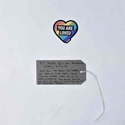 The image shows a heart-shaped sticker and a handwritten note with supportive messages attached.