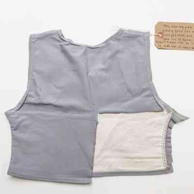 Grey chest binder displayed back-side-up on a white background. A square of fabric has been removed from the lower right side of the garment.