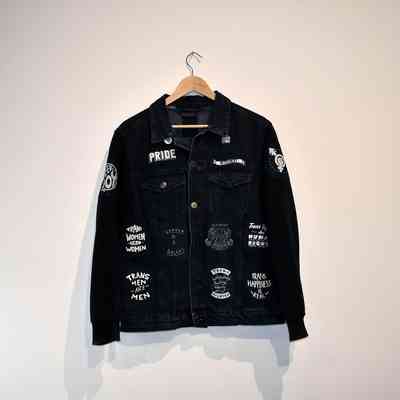 Black denim jacket with cotton padded arms covered with seventeen patches sewn on and three affixed pin badges.