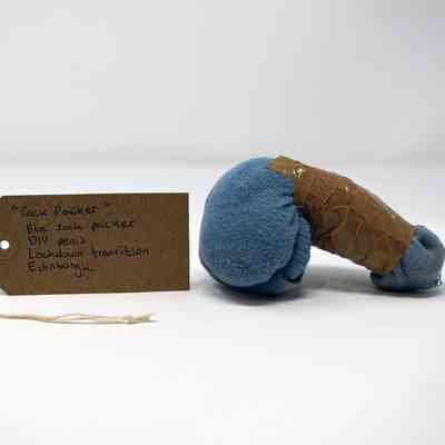 A homemade packer constructed from a blue sock and brown tape. With a brown, handwritten luggage tag.