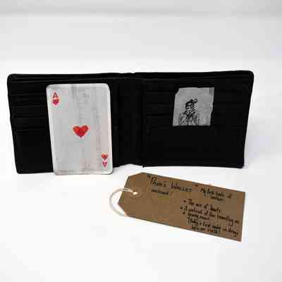 An open black wallet which has an Ace of Hearts card and a drawn portrait inside.