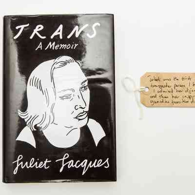 Dust cover of the book "TRANS A Memoir" by Juliet Jacques. The cover is a black background with white hand drawn outline portrait of a person with shoulder length hair.
