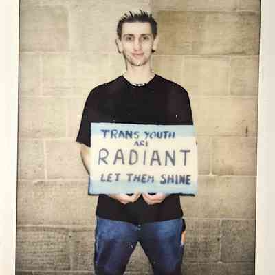 A person holds a sign advocating for trans youth.