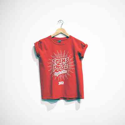Red T-shirt with a starbust design and the words "Trans Pride Brighton & Hove 2022" printed in white in the center.