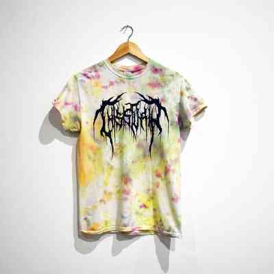 A tie-dye T-shirt with abstract lettering hangs on a wooden hanger against a plain white wall.