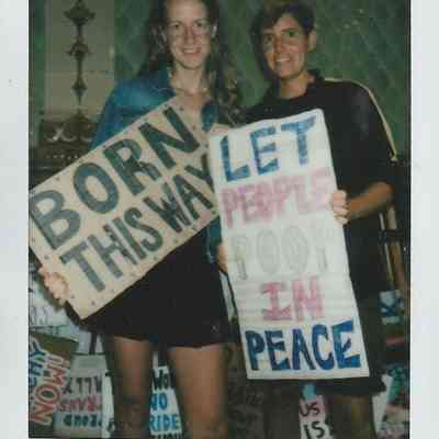 Two people are smiling and holding signs with messages at an event in Brighton.