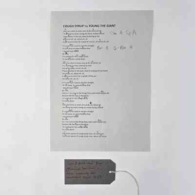 Lyrics to the song "Cough Syrup" by "Young the Giant" annotated with musical chords. With a brown, handwritten luggage tag.