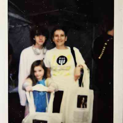 Three people are smiling for a Polaroid photo, labeled "TP Belfast 24".