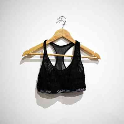 A black, sheer, Calvin Klein bra top on a wooden hanger.