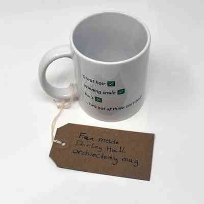 White ceramic mug with the text: "Great hair [tick], Winning smile [tick], Balls [cross] ... Two out of three ain't bad". With a brow, hand written luggage tag.