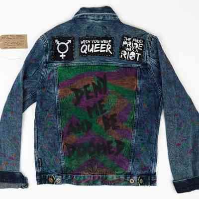 Modded denim jacket with queer/trans patches and slogan. With a brown handwritten luggage tag.