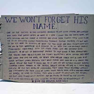 A cardboard placard with handwritten memorial about a person's activism and remembrance.