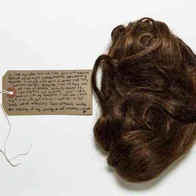 A handwritten note rests beside a bundle of brown hair.