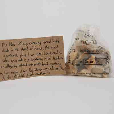 A plastic money bag filled with pebbles, with a brown handwritten luggage tag.