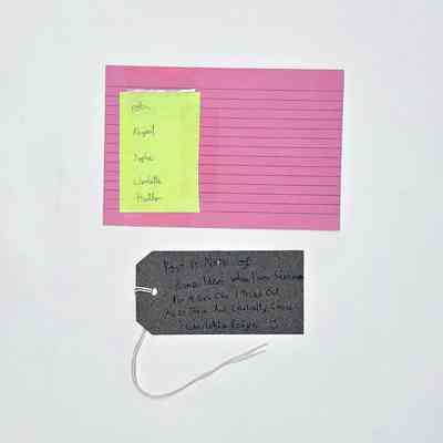 A list of names written on a yellow Post-It note that has been taped to a lined, pink index card. With a brown, handwritten luggage tag.
