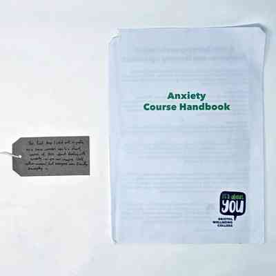 An Anxiety Course Handbook from Bristol Wellbeing College, with a brown handwritten luggage tag.