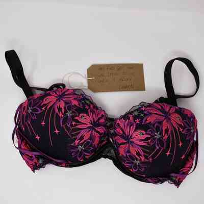 A black bra with pink and purple floral patterns is accompanied by a handwritten note luggage tag