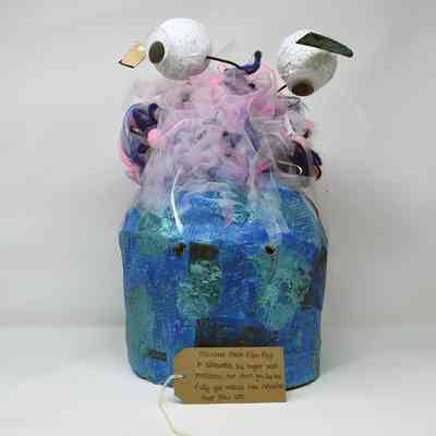 Handmade blue and green papier mache monster mask with colourful hair and googly eyes on stalks. Also a brown luggage tag.