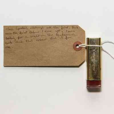Silver lipstick tube with red stripe on the bottom. "MAX FACTOR X" is written in white text on the front.