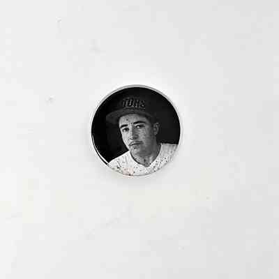 Small black badge showing a black and white portrait of Darcy wearing a white tshirt and black hat.