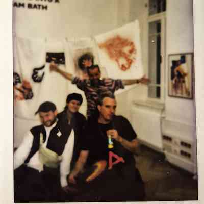 Four people are posing together in a room with artwork.