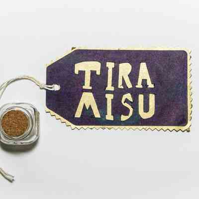 A glass jar with a cork in it next to a label which says TIRA MISU.
