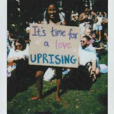 A person holds a sign reading "It's time for a love uprising" at London Trans Pride.