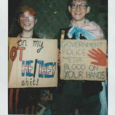 Two people are holding placards and grinning at the camera.