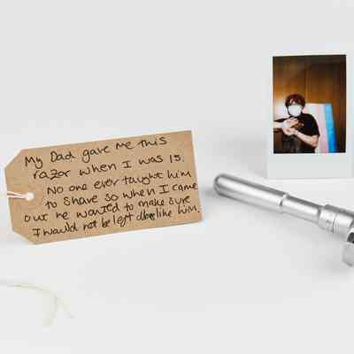 A razor, handwritten note, and photograph are carefully arranged on a white surface.