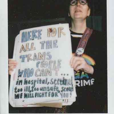 A person holds a sign supporting trans individuals during a rally in York on October 14, 202