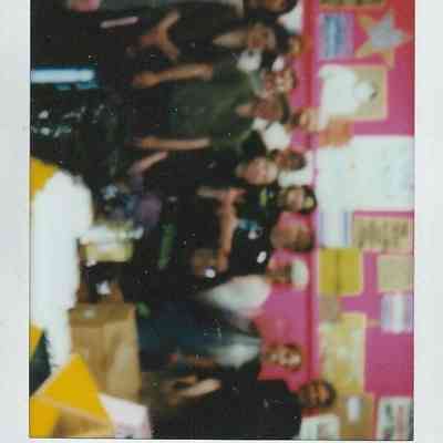 A group of people poses together in a colorful room with various posters on the walls.