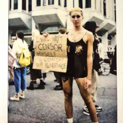 A person stands holding a sign saying, "I will not censor myself to comfort your ignorance".