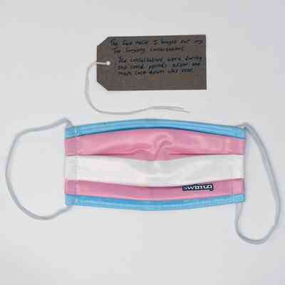 A colorful face mask lies beneath a note, possibly explaining its significance or context.