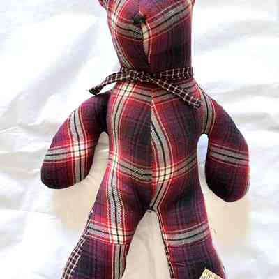 A plaid teddy bear with button eyes and scarf sits on a white background.