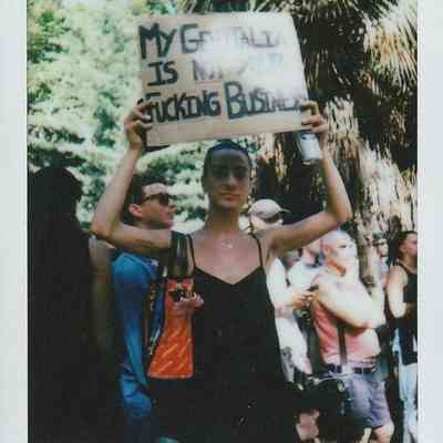 A person is holding a sign that reads, "My genitalia is not your business".