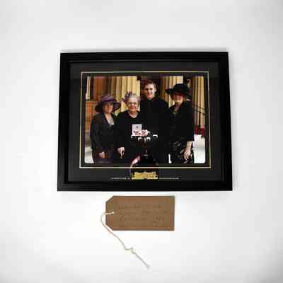 Framed photograph of four people and a brown tag.