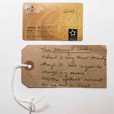 Gold coloured plastic membership card for Thai Airways & tag. Card has small scratches generally over surface, residue from sticky label on reverse and finger marks.