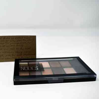 A makeup palette and a handwritten note are placed on a white surface.