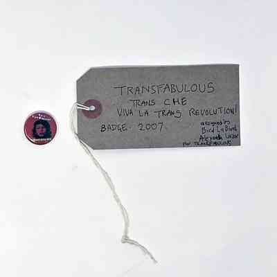 Pink badge with Che Guevara style picture of head wearing beret with blue eye shadow & slogan "Viva la Trans Revolution! Transfabulous